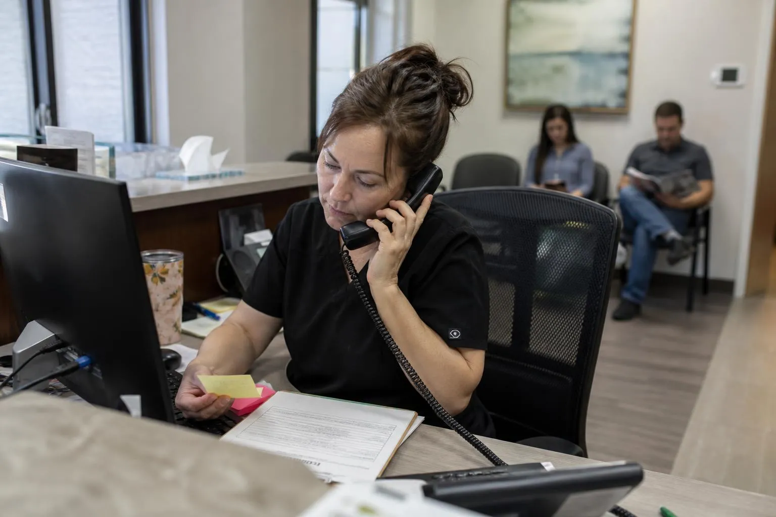 A front desk team member at a multi-provider practice taking a call between patient check-ins