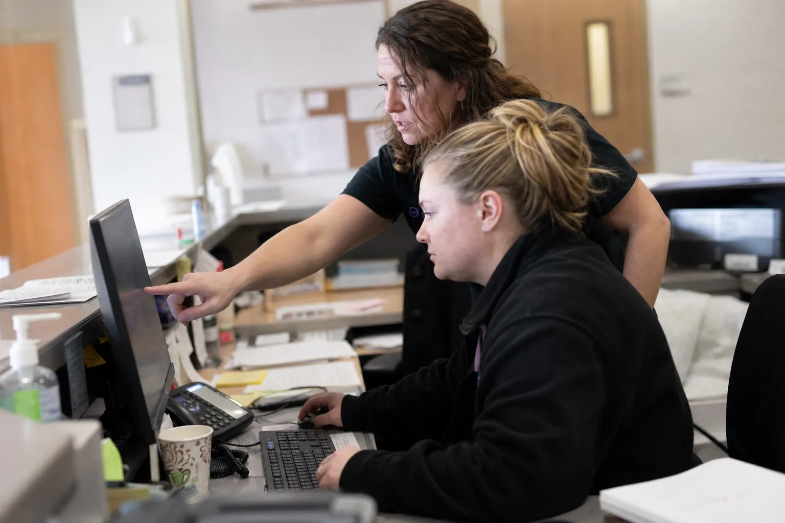 Front desk staff at a medical practice reviewing the overnight message queue on a monitor first thing in the morning