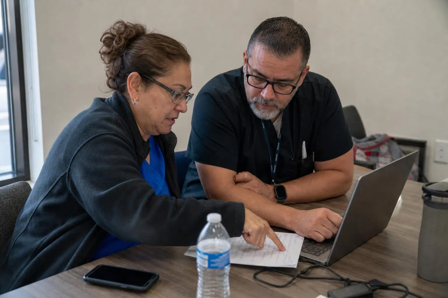 Two clinic administrators comparing voice AI vendor notes on a laptop