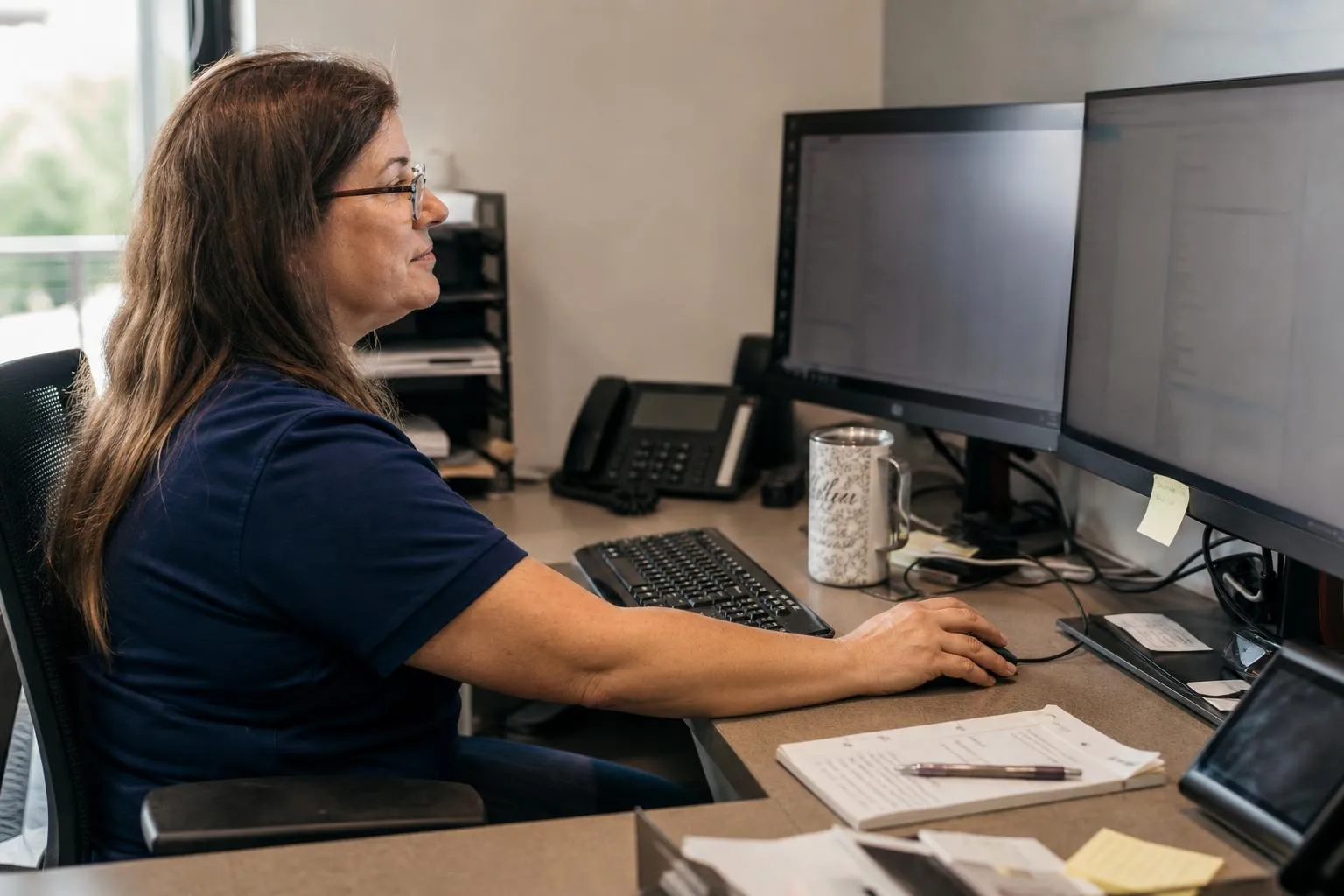 A practice administrator reviewing a task list and call notes on a monitor.