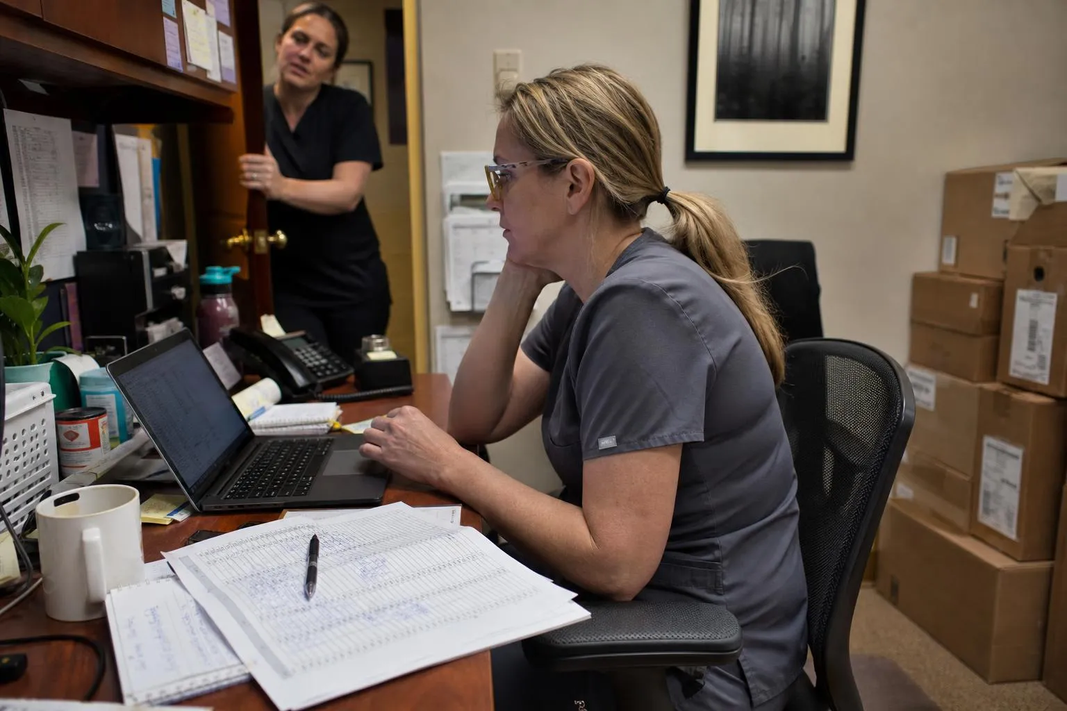 Practice operations lead reviewing a multi-location call report on a laptop in a dental office back room