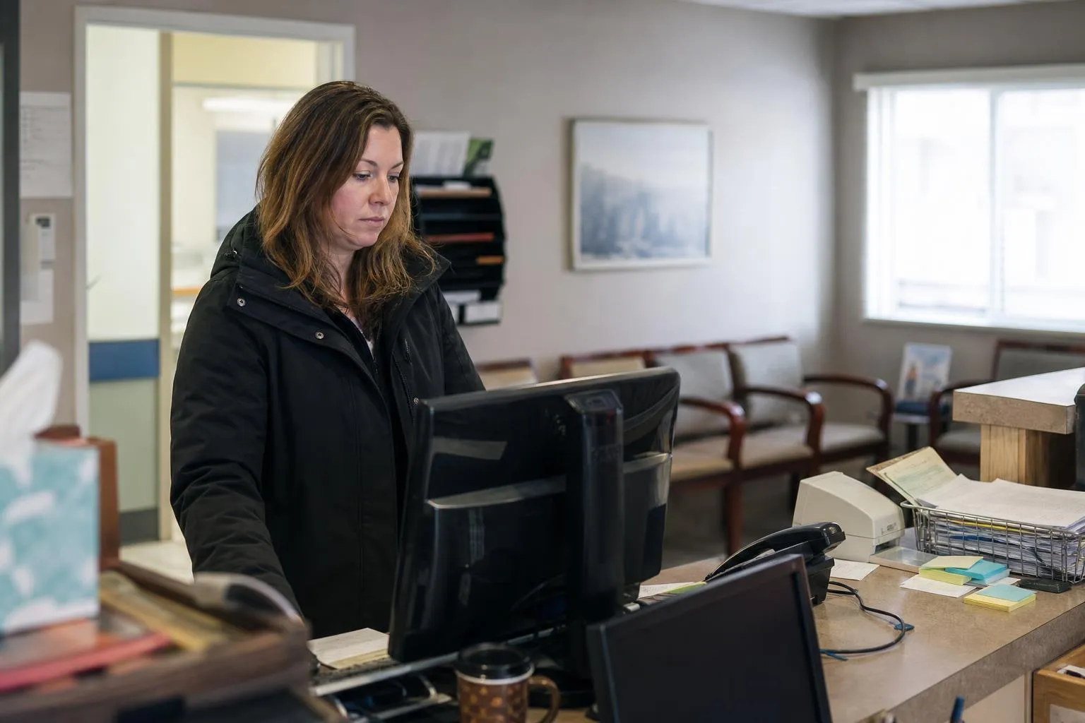 A medical office coordinator reviewing overnight phone messages on a computer before the clinic opens