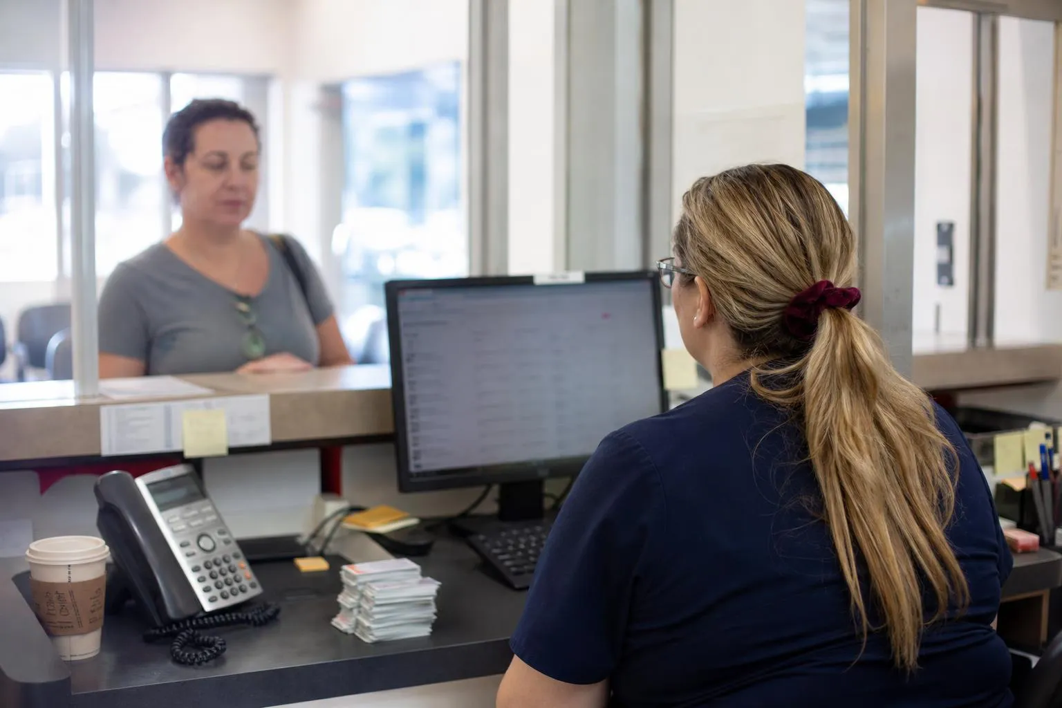 A front desk coordinator at a medical practice reviewing new patient inquiries on a monitor